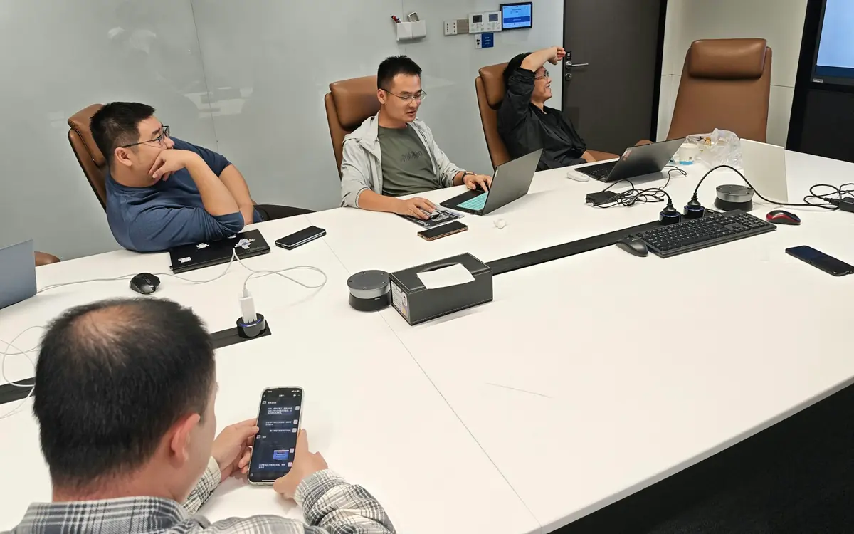Management team in a meeting room with laptops and phones planning a business software rollout